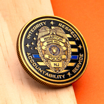 Gold and black Wharton Mine Hill Police challenge coin featuring an eagle shield and blue line accent.