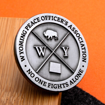 Antiqued silver challenge coin for the Wyoming Peace Officer's Association featuring a bison, crosshairs, and letters W Y.