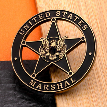 A black and gold cutout challenge coin featuring the United States Marshal five-point star and eagle emblem.