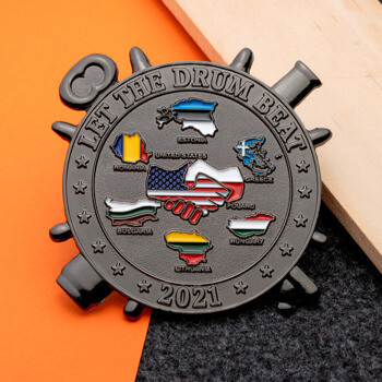 Black metal challenge coin featuring a handshake between US and Poland flags surrounded by European country maps and the text Let the Drum Beat 2021.