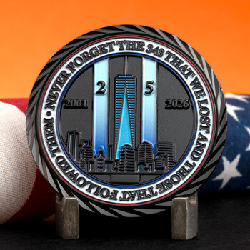 September 11 memorial challenge coin featuring the NYC skyline, tribute beams, and 25-year remembrance dates beside an American flag.