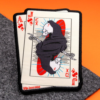 Embroidered playing card patch depicting a Grim Reaper Jack of Clubs and Ace of Clubs with a black merrowed border.