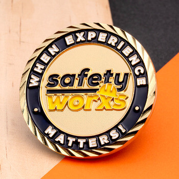 Gold challenge coin featuring a hard hat logo with the text Safety Worxs, When Experience Matters!