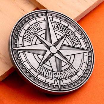 Antique silver challenge coin featuring a nautical compass rose and the words Honor, Educate, and Entertain engraved along the segments.